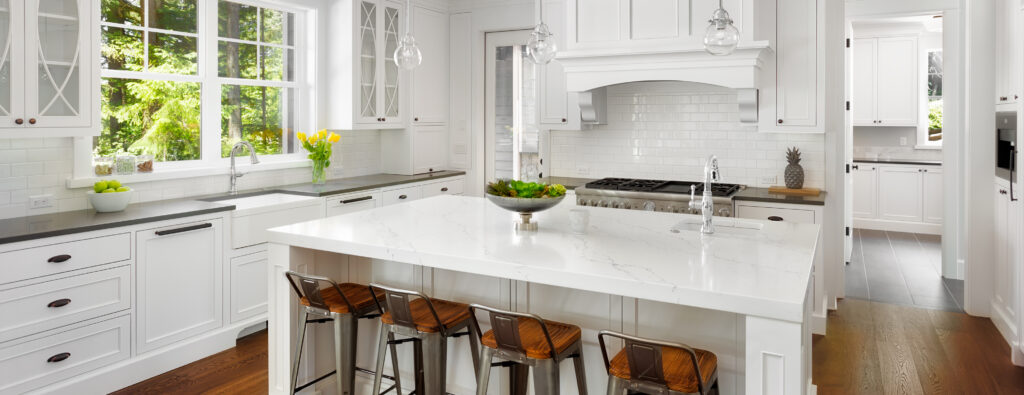 White Kitchen Interior with Island, Sink, Cabinets, and Hardwood Floors in New Luxury Home